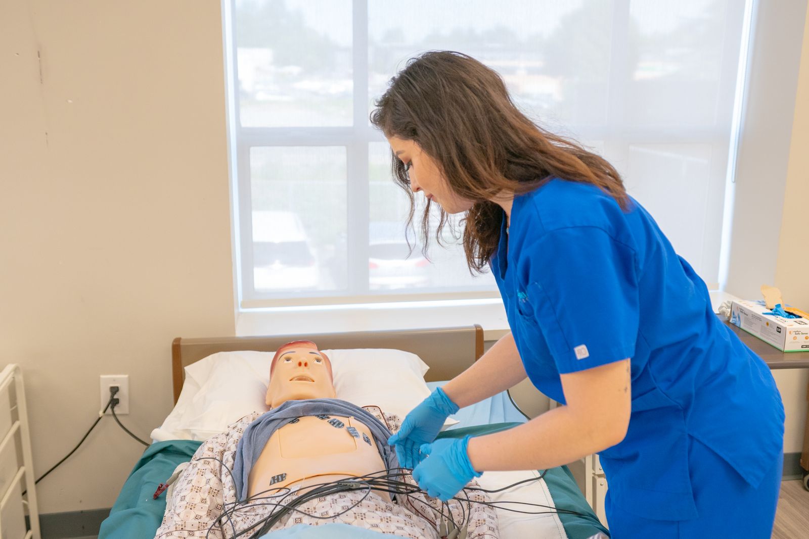Infirmière qui pose des électrodes sur un mannequin de simulation